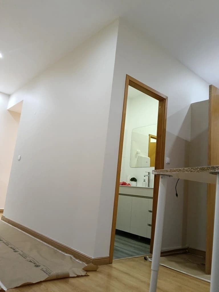 Corredor pintado de branco com porta de madeira