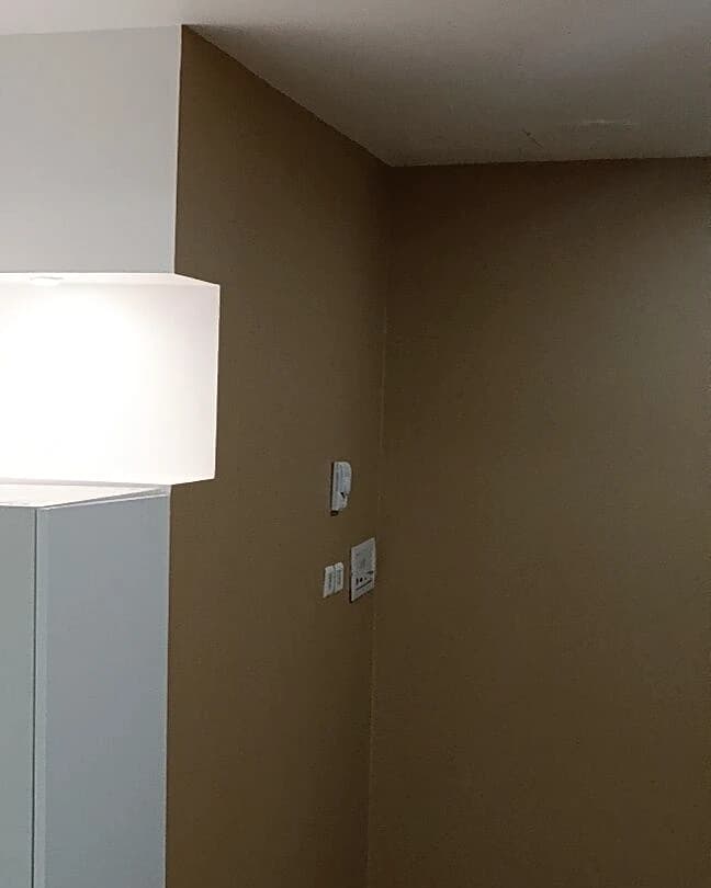 Parede pintada em castanho-claro com teto branco e móvel branco